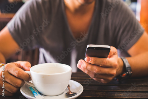 Man using smart phone and drinking coffee