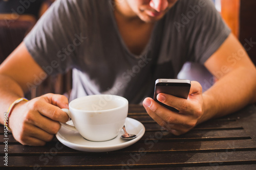 Man using smart phone and drinking coffee