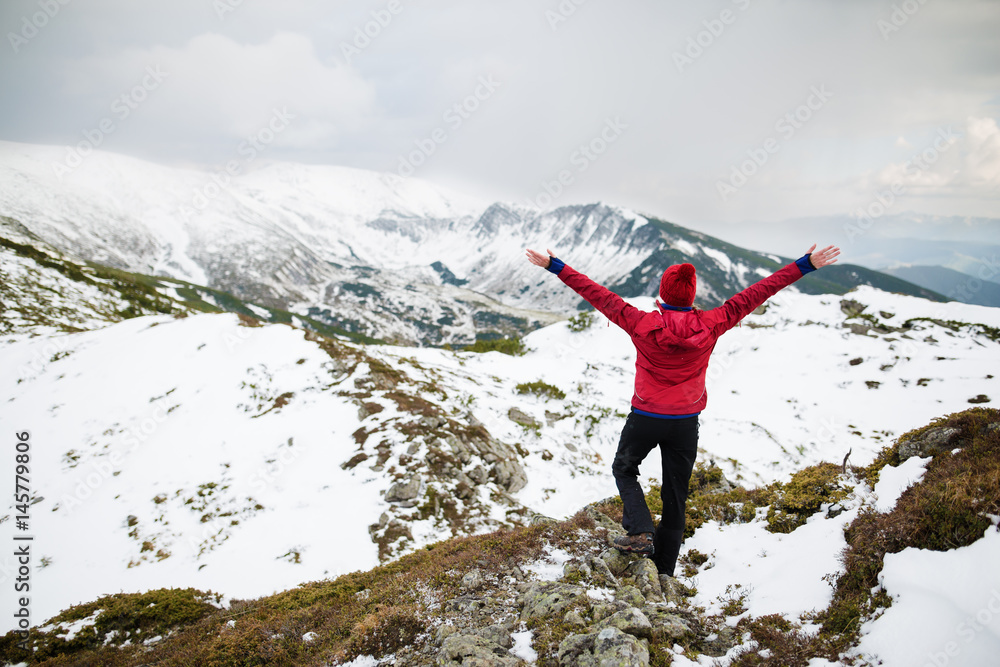 Hiker woman standing with hands up achieving the top. Winter hiking. Recreation fitness and healthy lifestyle outdoors in beautiful snowy nature. Hiker woman standing with hands up achieving the top. Winter hiking. Recreation fitness and healthy lifestyle outdoors in beautiful snowy nature.