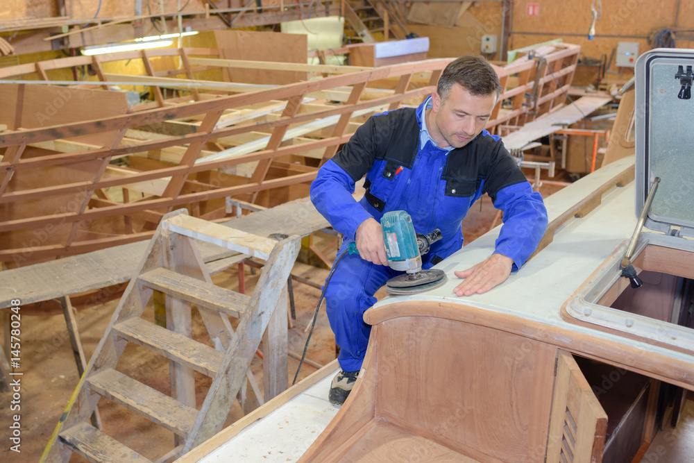 Man using sander on wooden boat Man using sander on wooden boat
