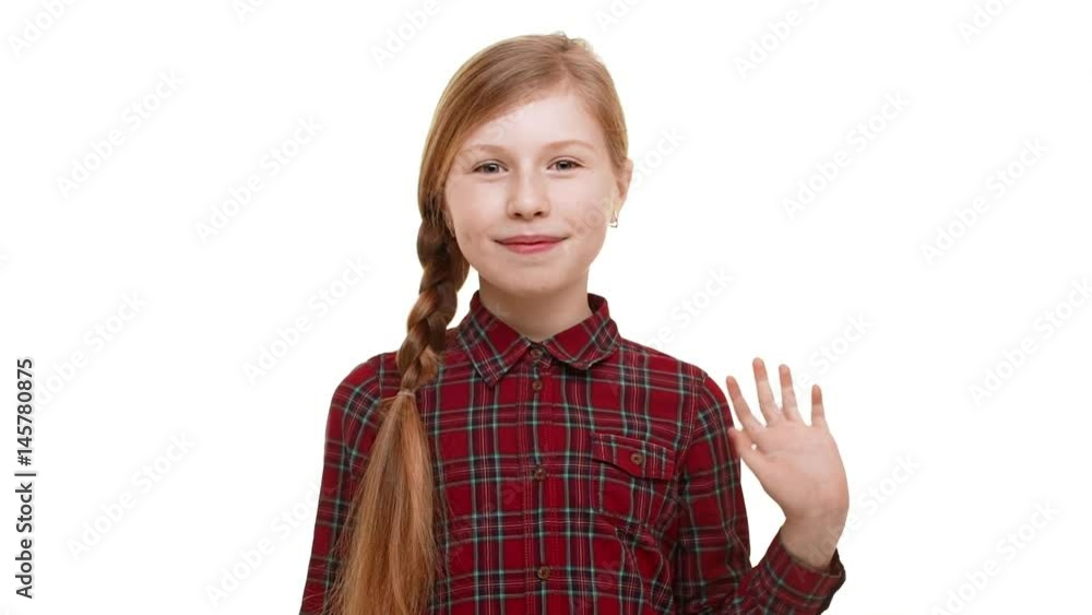 Cute beautiful elementary-school aged girl with plait of hair standing on white background waving hand and smiling in slowmotion Cute beautiful elementary-school aged girl with plait of hair standing on white background waving hand and smiling in slowmotion