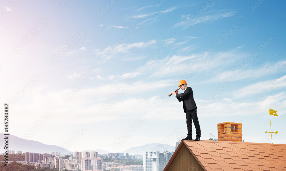 Engineer man standing on roof and looking in spyglass. Mixed media Engineer man standing on roof and looking in spyglass. Mixed media