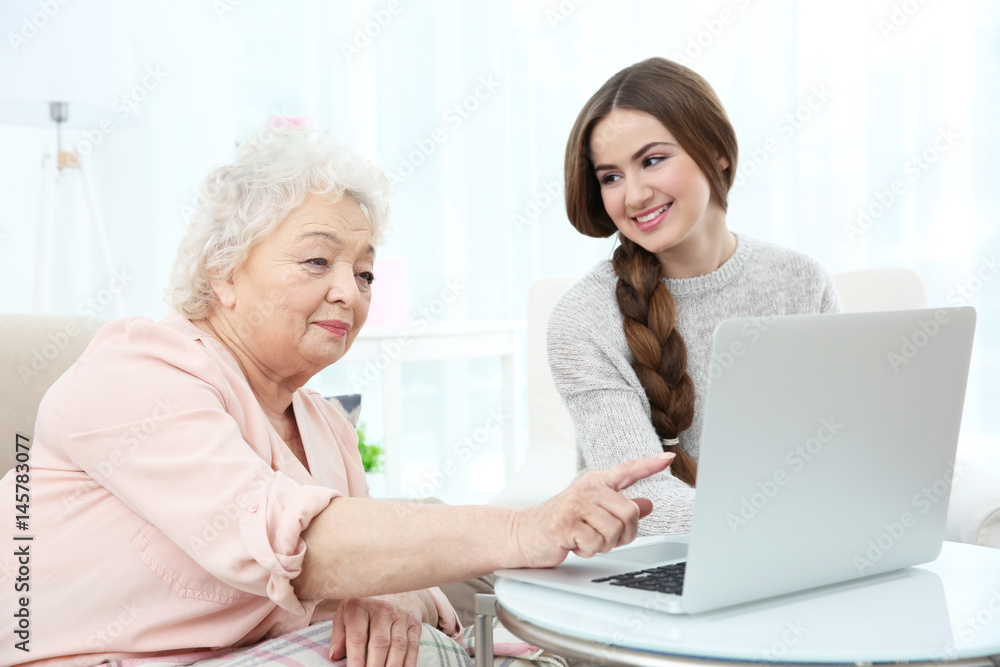 Beautiful girl with grandmother using laptop at home Beautiful girl with grandmother using laptop at home