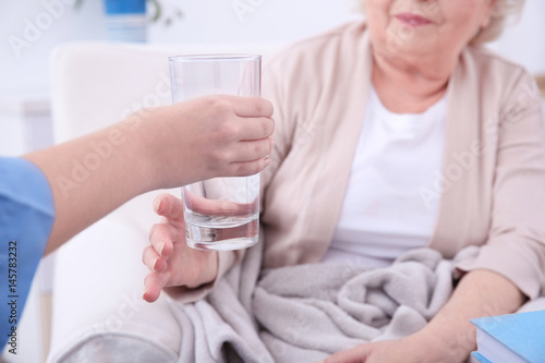 Nurse giving glass of water to elderly woman