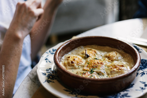 Person eating raviolis with gratin cheese, in restaurant