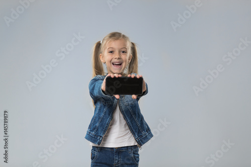 Little Teenage Girl Show Cell Smart Phone Screen With Empty Copy Space, Small Excited Happy Smiling Child Isolated Over Gray Background