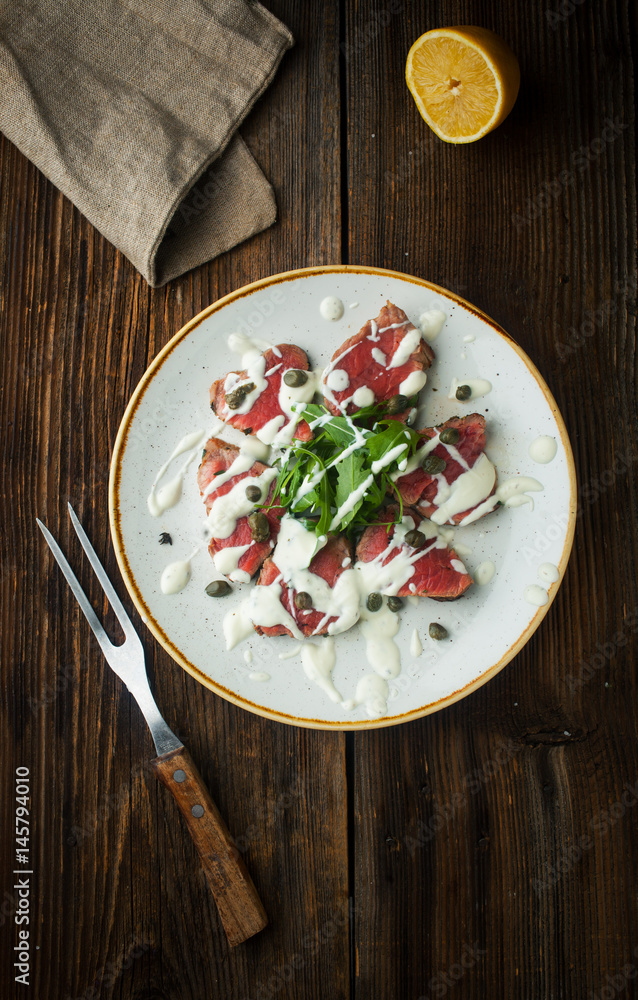 Carpaccio of beef with spices, seasonings and capers on a plate