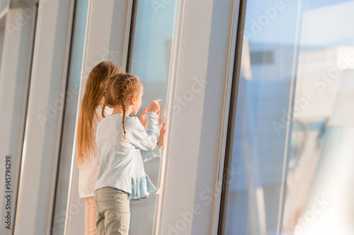 Little kids together in airport waiting for boarding near big window