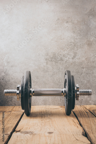  iron dumbbell on a wooden plank with gray background