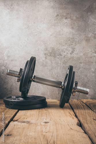  iron dumbbell on a wooden plank with gray background