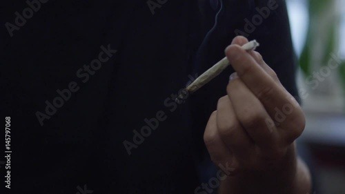 A man smoking a marijuana weed joint in slow motion inhaling smoke