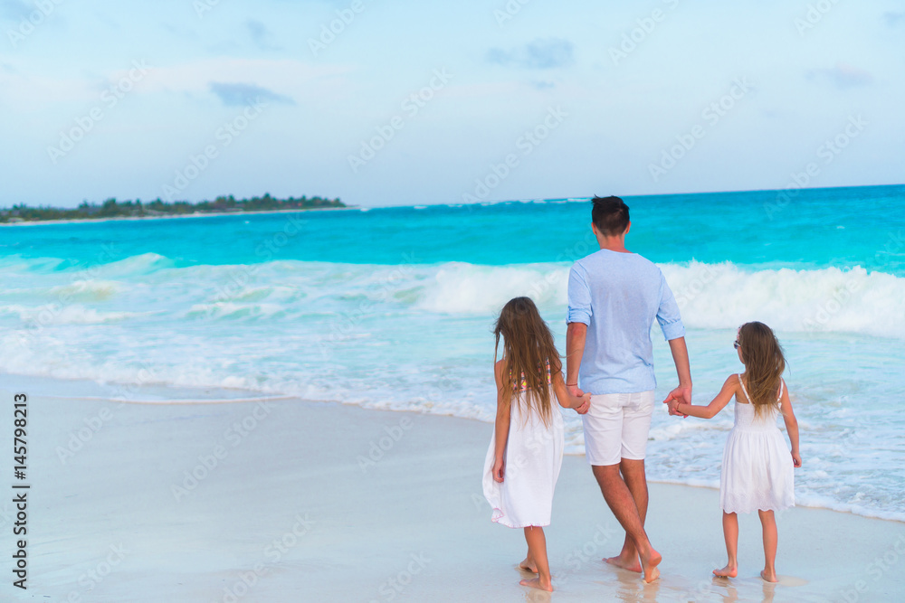 Family walking on white beach on caribbean island in the evening