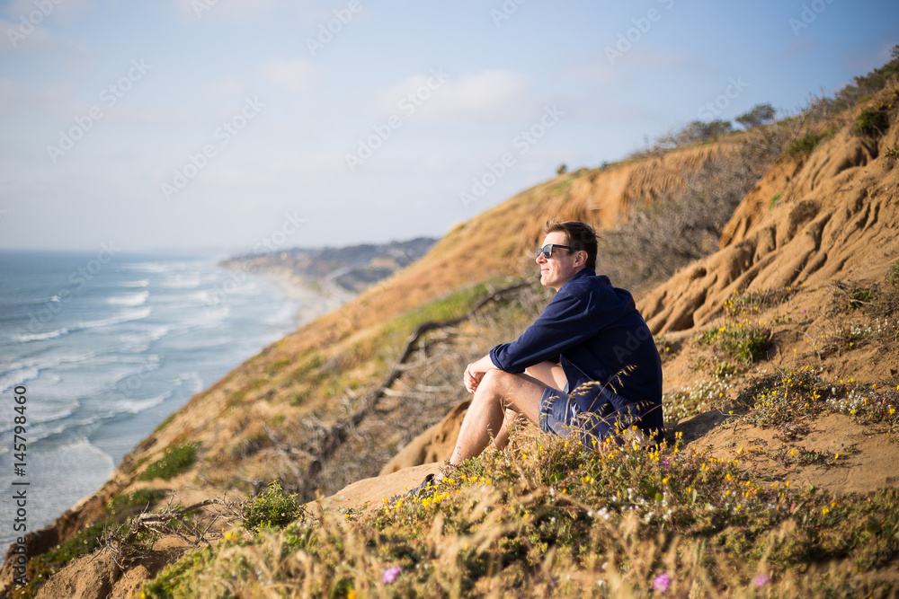 Young man, boy sitting on the cliff in San Diego, California. Sunset cliff. Meditation Young man, boy sitting on the cliff in San Diego, California. Sunset cliff. Meditation