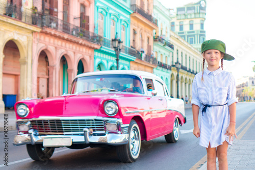 Adorable little girl in popular area in Old Havana, Cuba. Portrait of kid background vintage classic american car © travnikovstudio