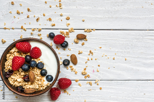 bowl of greek yogurt with oat granola, fresh raspberries, blueberries and nuts