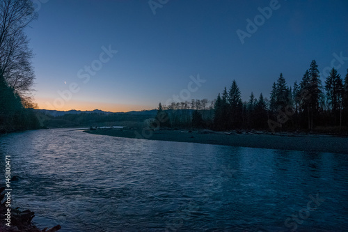 Fast flowing river on the background of the evening sky. Dark blue rough river. Scenic landscape of Olympic National Park, Washington state, USA