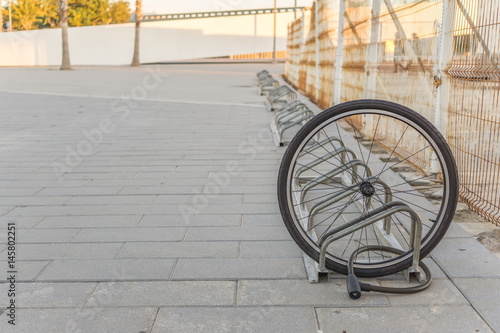 Stolen bicycle, Chained front bicycle wheel locked. A damaged bike wheel is all that is left, a single bicycle wheel on the street due to stealing.