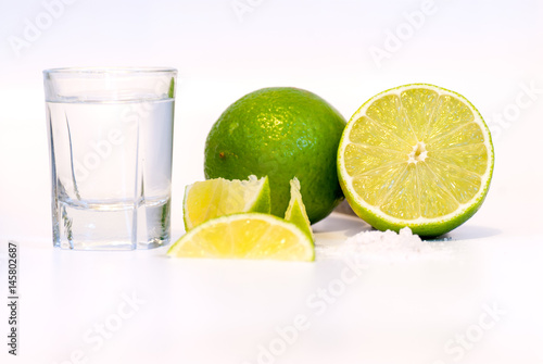 glass with tequila lime slices and salt on white background with copy space