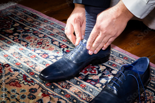 Groom wearing shoes on wedding day tying the laces