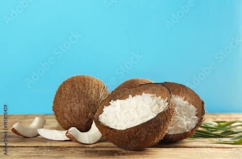 Grated coconut in shell and whole nuts on wooden table