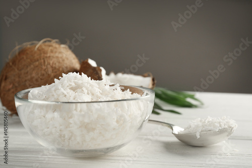 Glass bowl with coconut flakes on wooden table