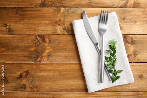 Table setting with silver cutlery and napkin on wooden background