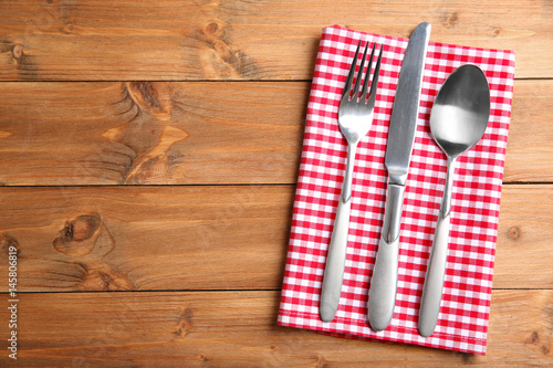 Table setting with silver cutlery and napkin on wooden background