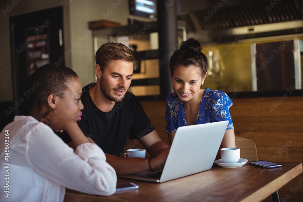 Friends using laptop while having coffee Friends using laptop while having coffee