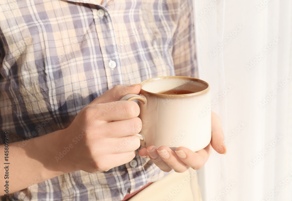 Woman with cup of hot tea near window, closeup Woman with cup of hot tea near window, closeup
