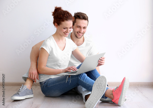 Happy young couple with lap...