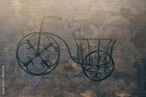 a small metal bicycles blended on roses and wood planks background, filtered tones