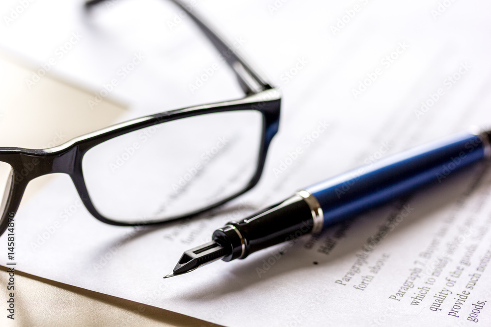 Signing the contract with pen and glasses in business work on office desk Signing the contract with pen and glasses in business work on office desk