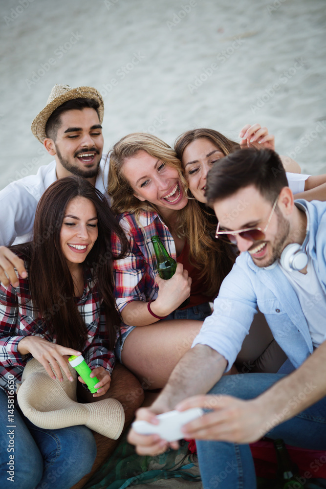 Happy young group of people taking selfies on beach