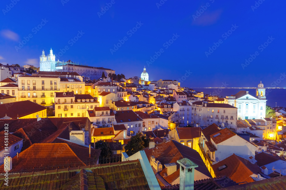 Panoramic view of Alfama, the oldest district of the Old Town, with Monastery of Sao Vicente de Fora, Church of Saint Stephen and National Pantheon during evening blue hour, Lisbon, Portugal