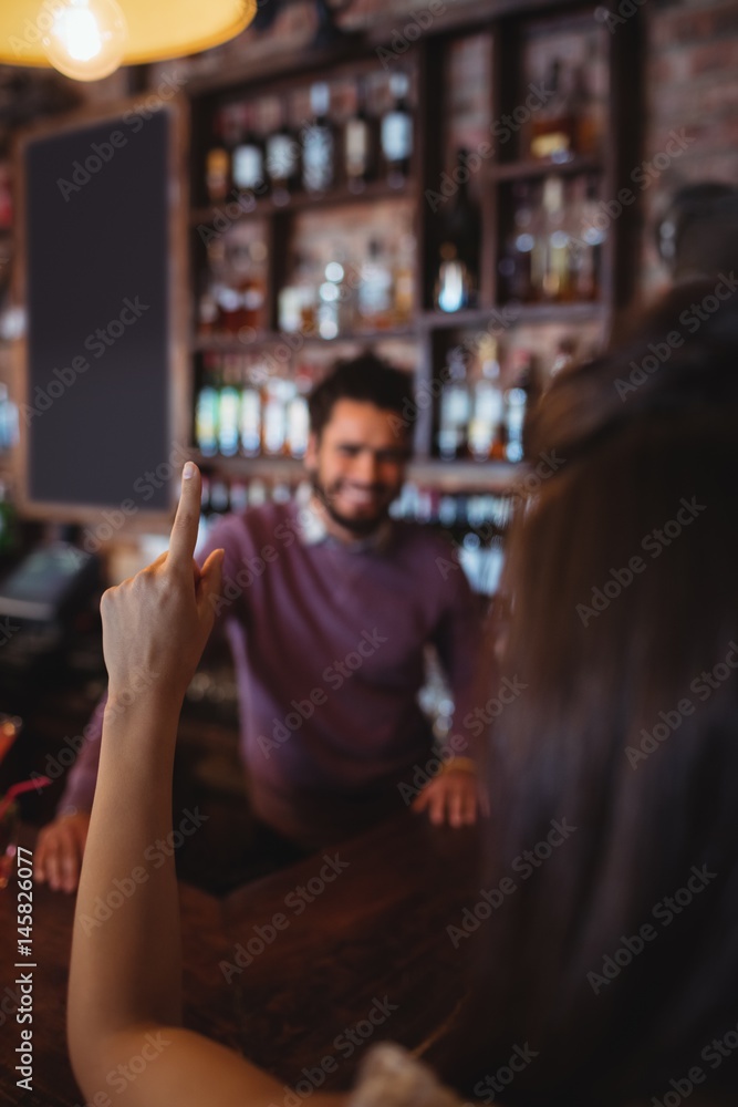 Woman asking for a drink to bar tender Woman asking for a drink to bar tender