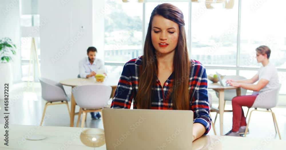 Female executive sitting at desk and using laptop Female executive sitting at desk and using laptop