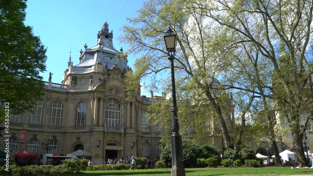 Tourists are resting on the green lawn in front of the ancient building