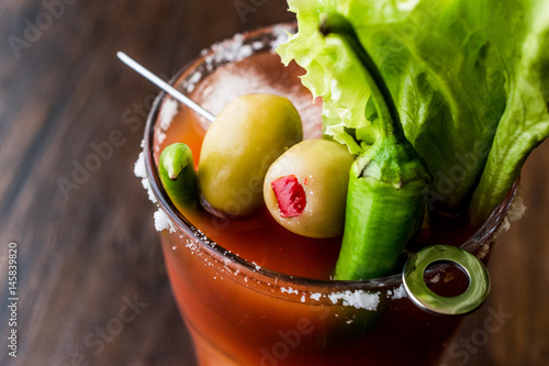 Bloody Mary Cocktail with green olive, pepper, lettuce, salt and ice.