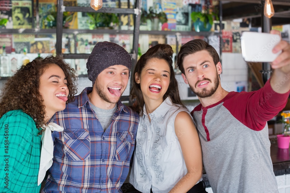 Fototapeta premium Friends making faces while talking selfie in restaurant