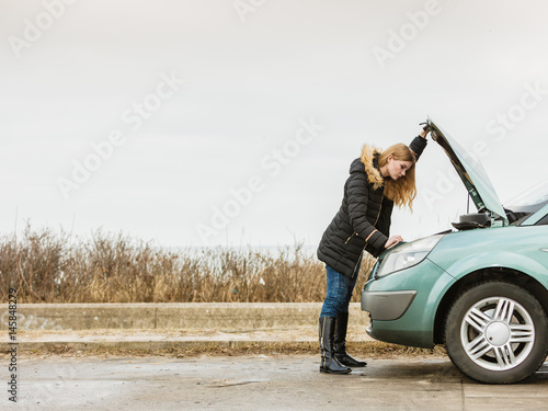Blonde woman and broken down car on road