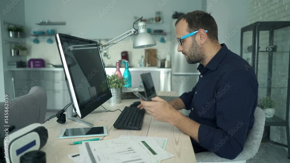 Young man working with smartphone and pc computer sitting by tablet at home
Young man working with smartphone and pc computer sitting by tablet at home