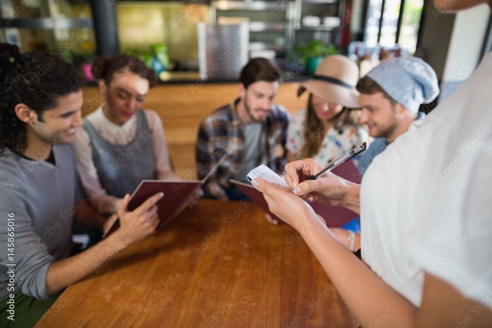 Waitress taking orders of customers in restaurant Waitress taking orders of customers in restaurant