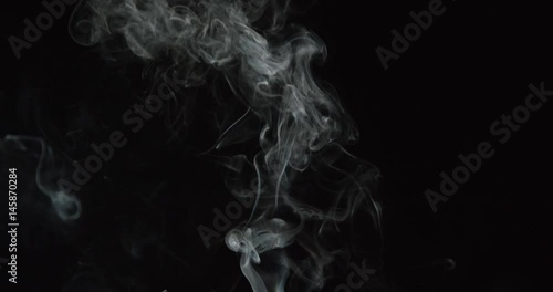 Candle smoke wisps rise in smooth lines and grow turbulent against black