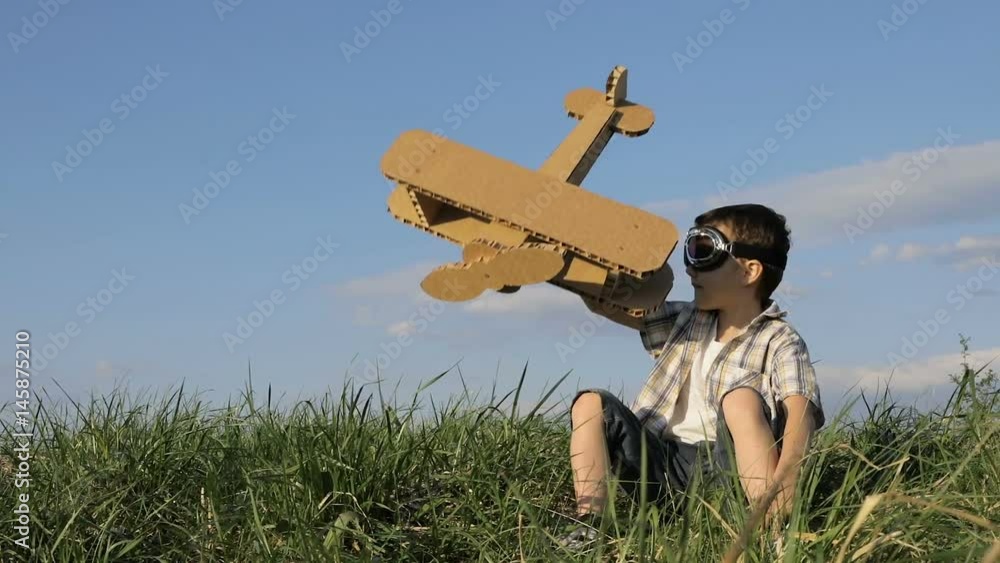 Little boy playing with cardboard toy airplane in the park at the day ...