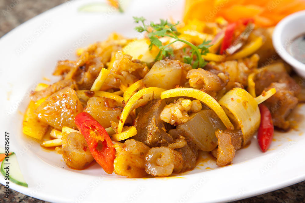 Fried sauteed beef tendon with onion and chili on white dish Fried sauteed beef tendon with onion and chili on white dish