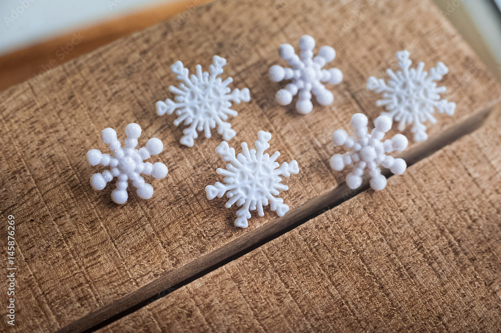 Fototapeta premium Snowflakes on a wooden background. Snow in the macro. Buttons in the form of snowflakes on a wooden board