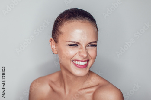 Portrait of beautiful smiling woman with make up on white background. Naked shoulders.