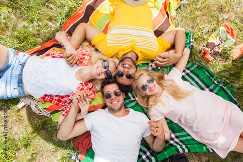Happy people group young friends lying down on picnic blanket outdoor, two couple summer sunny day smile top angle view