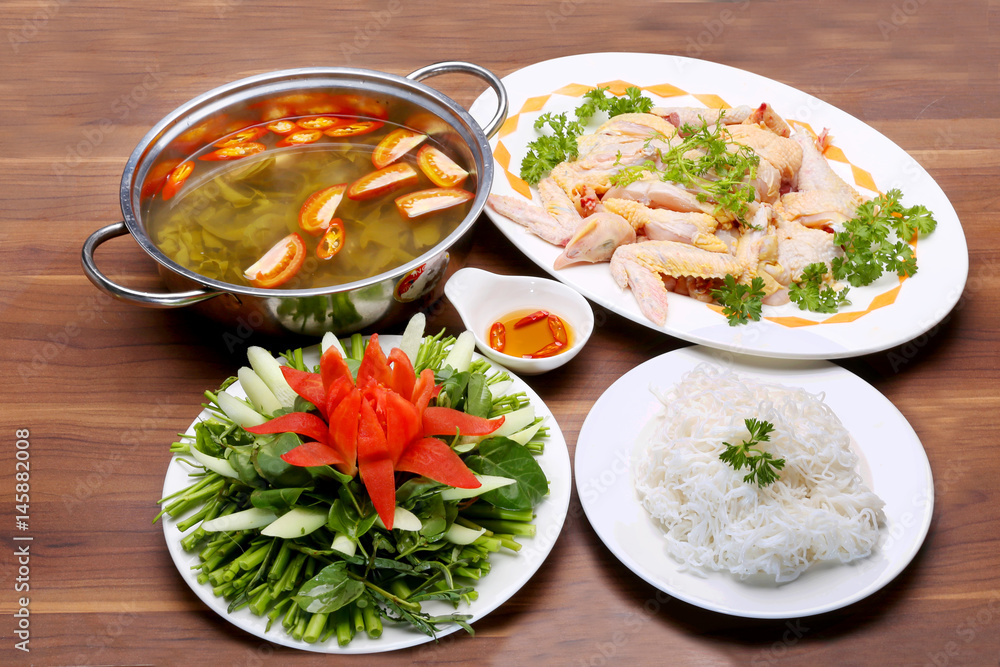 Prepared hot pot of chicken with sour leaves and vegetables on table Prepared hot pot of chicken with sour leaves and vegetables on table