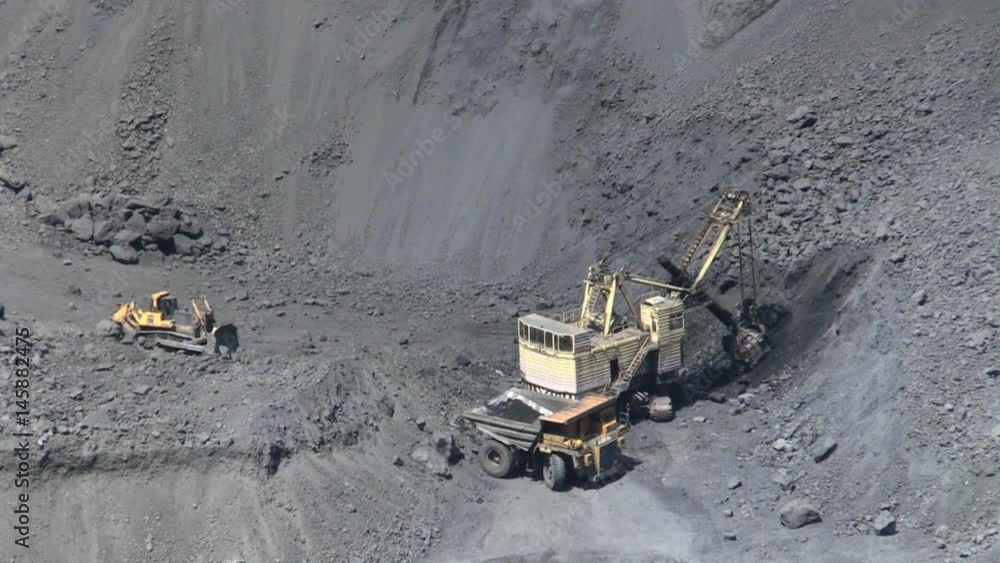Excavator loading iron ore into the heavy dump truck on the open cast mine. Excavator loading iron ore into the heavy dump truck on the open cast mine.